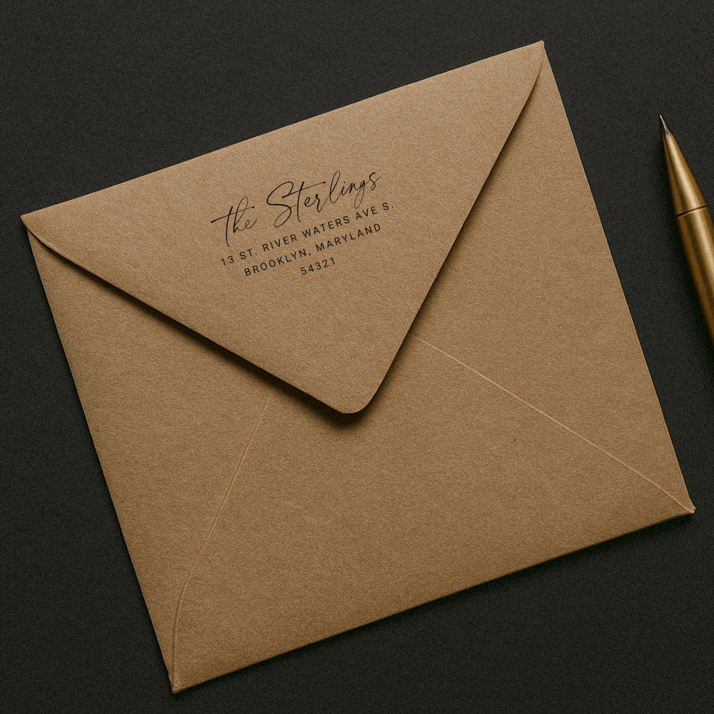 Custom rubber stamp with calligraphy return address stamped on kraft envelope and a gold pen