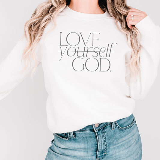 Blonde woman wearing a white Christian sweatshirt with "Love God" message in stylish serif font, perfect for expressing faith and personal style