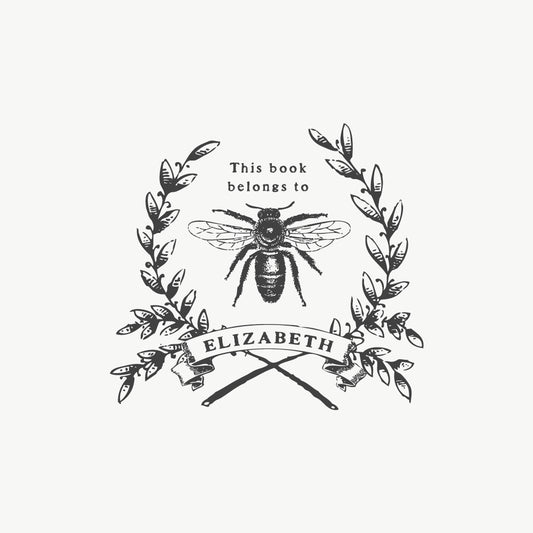 Custom book stamp featuring a vintage bee illustration and wreath, with a vintage font that reads "This book belongs to"
