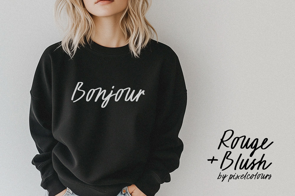 Blonde woman wearing a black "Bonjour" sweatshirt with handwritten script font, in a chic, minimalist style